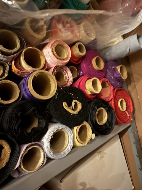 A box of fabric rolls stood on end — velvet, satin and cotton in pink, purple, black and cream.