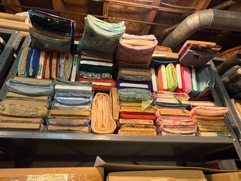 Metal shelving stacked with folded fabric in every colour, sorted by shade.